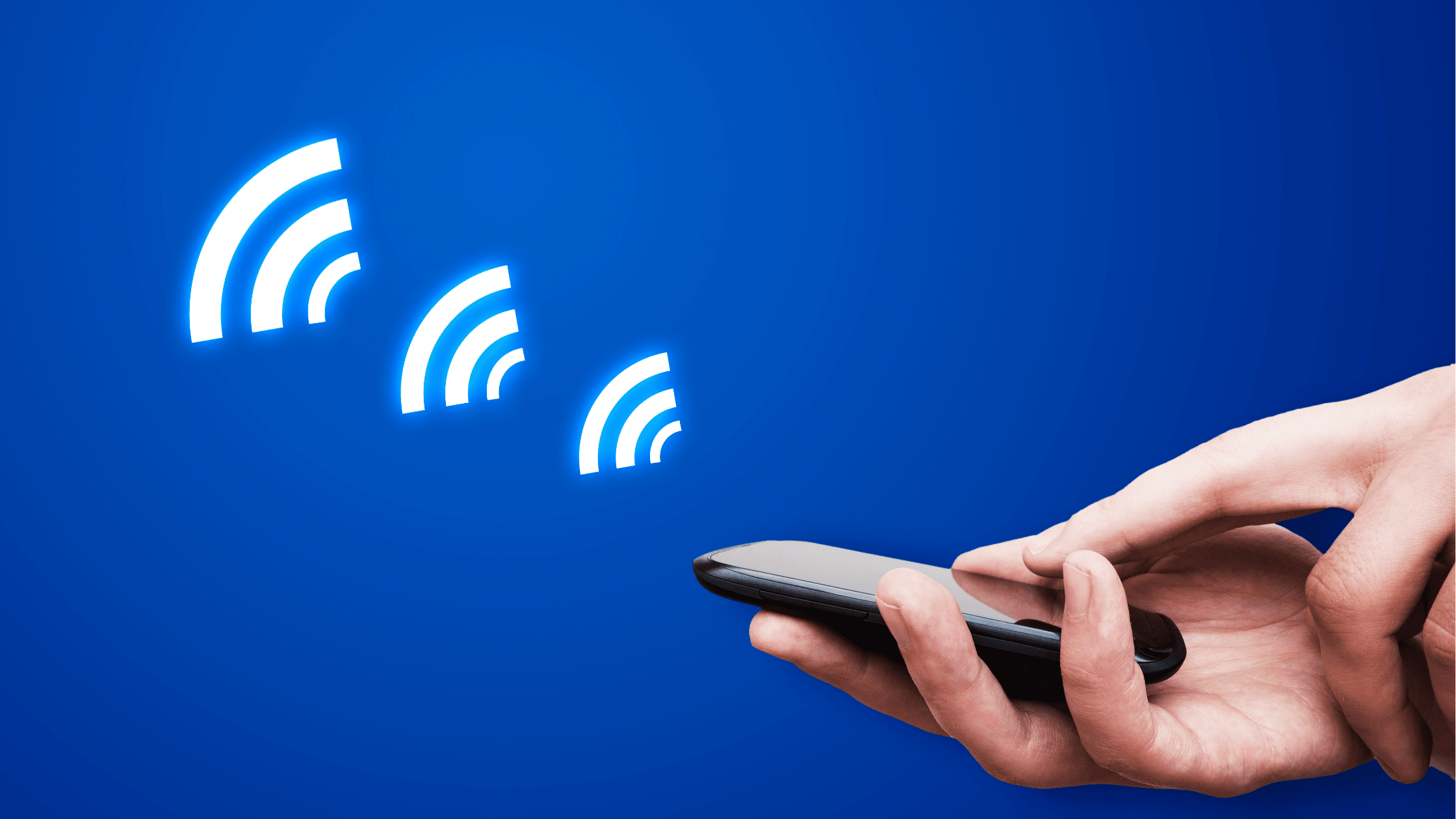 Hand holding a smartphone with a blue background, emitting three glowing signal icons, symbolising wireless connectivity.